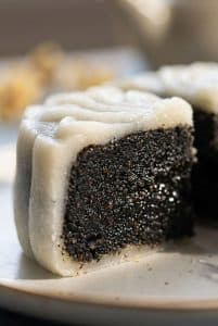 Macro extreme close-up of a cut snow skin mooncake cross-section revealing a dense, glossy black sesame seed paste filling inside a translucent chewy white skin