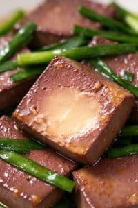 Macro cross section of tender pork blood curd showing a smooth, custardy interior with Chinese chives.