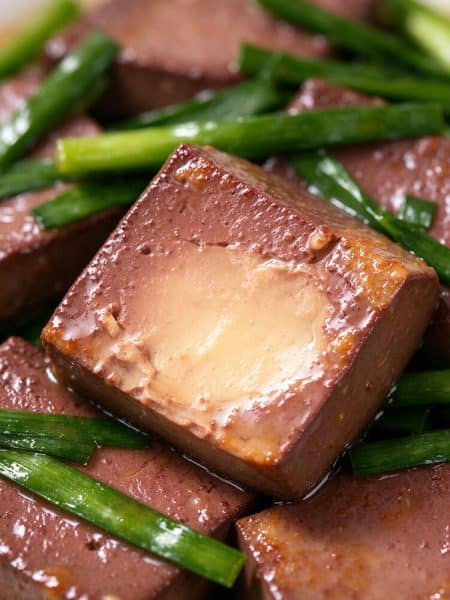 Macro cross section of tender pork blood curd showing a smooth, custardy interior with Chinese chives.