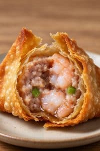 Macro close-up cross section of a fried wonton with a crispy blistered shell and juicy shrimp pork filling.
