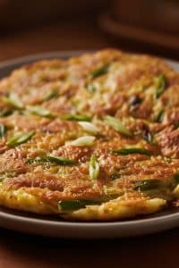 Extreme macro close-up of the crispy golden crust and tender noodlefish interior of Chinese silverfish egg pancake garnished with scallions.