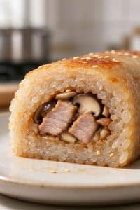 Close-up cross section of a pan-seared sticky rice roll showing the crispy outer layer and juicy pork mushroom center.