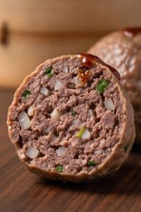 Macro cross-section of a steamed dim sum beef ball displaying its springy texture, tender meat fibers, and crunchy water chestnut bits.