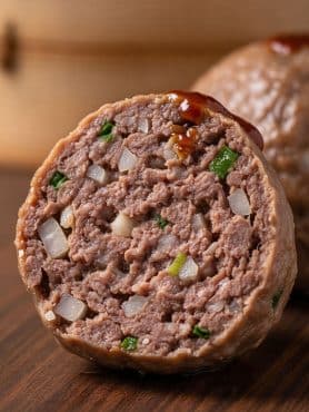 Macro cross-section of a steamed dim sum beef ball displaying its springy texture, tender meat fibers, and crunchy water chestnut bits.